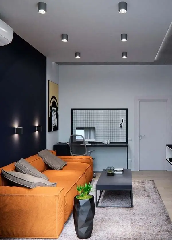 Nessa sala de estar a parede preta foi contrastada com o sofá laranja de três lugares